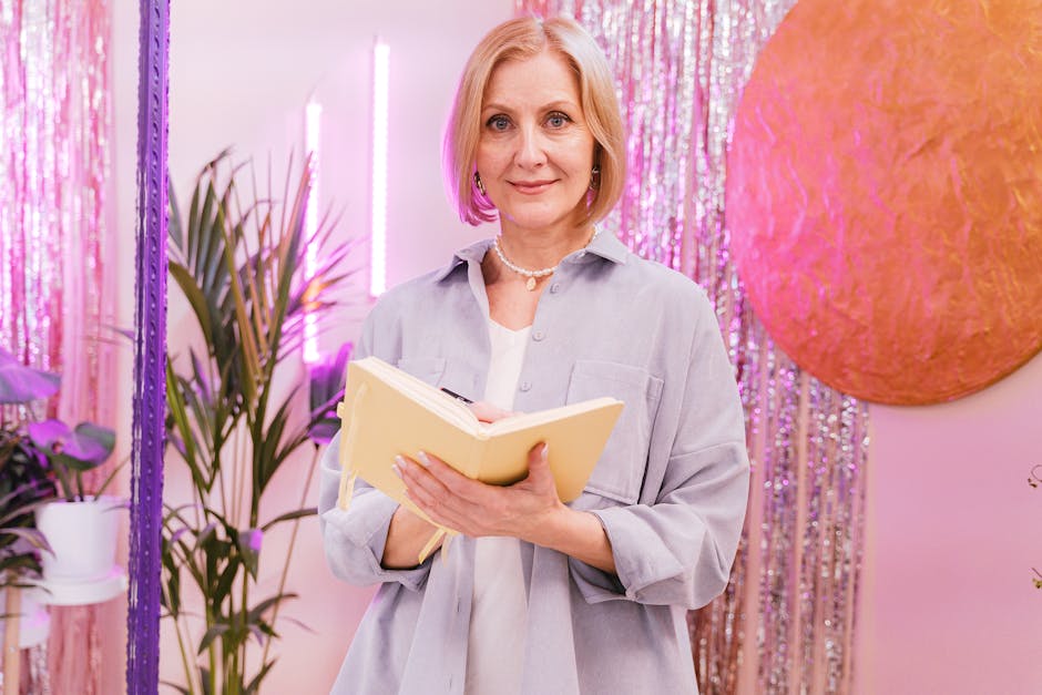 Mature woman with notebook standing against a colorful backdrop indoors. Ideal for lifestyle themes.
